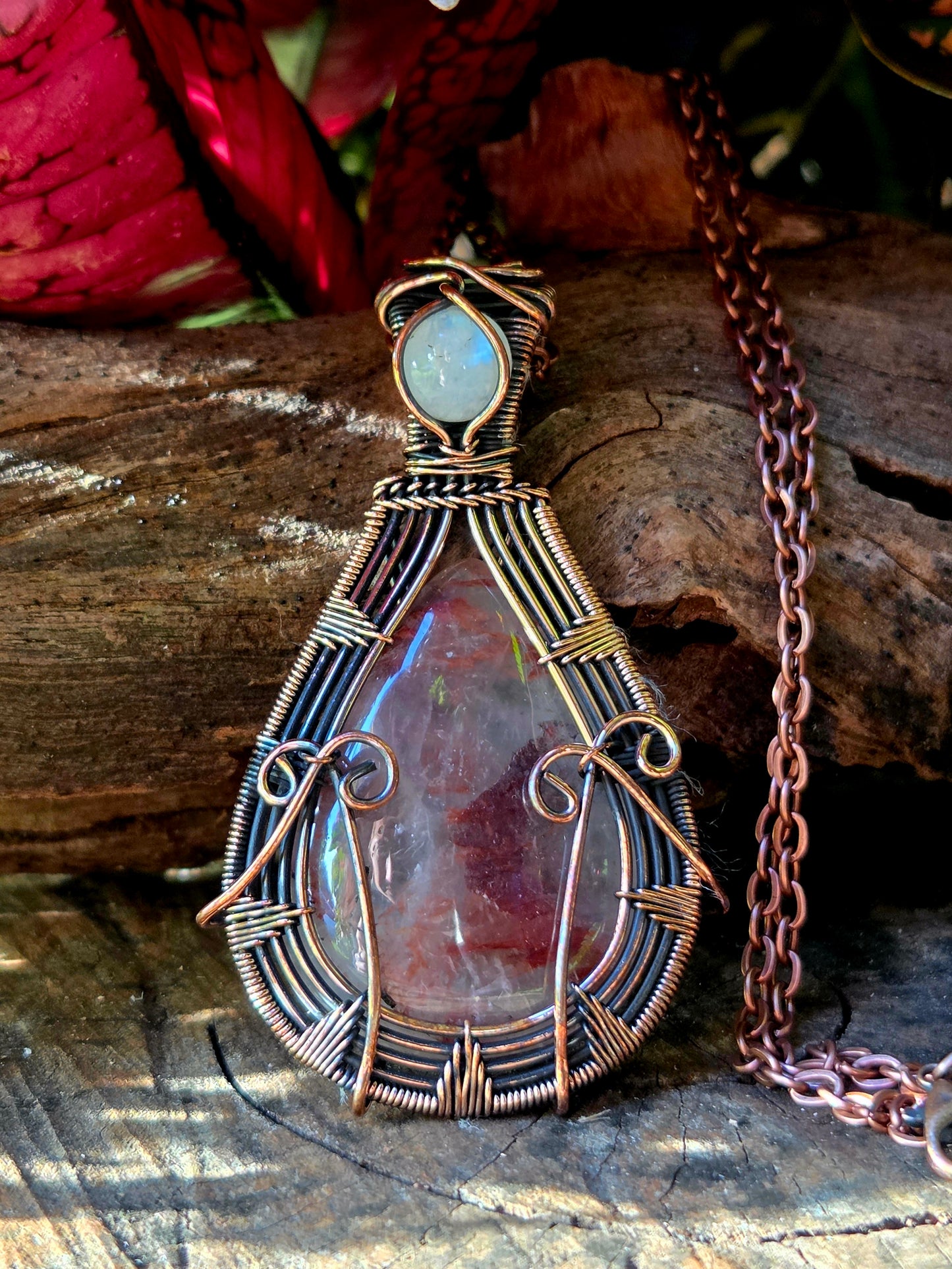 Copper necklace on a natural wooden surface with red leaves in the background