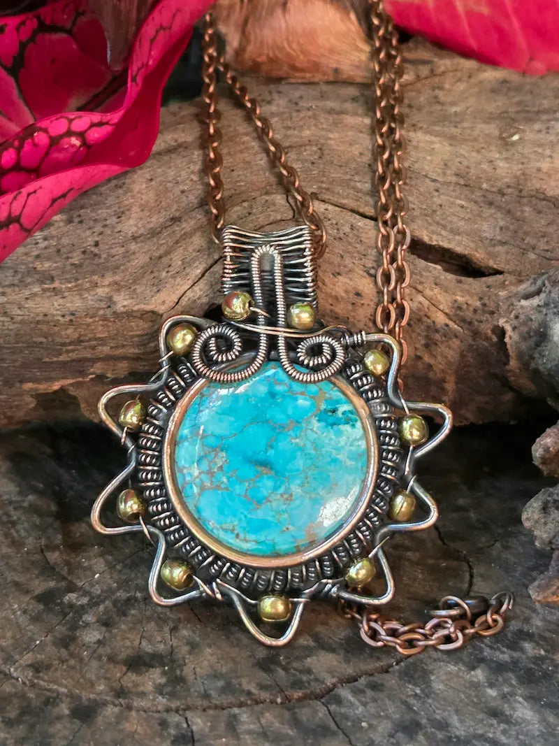 Turquoise crystal copper necklace on a natural surface with red leaves in the background