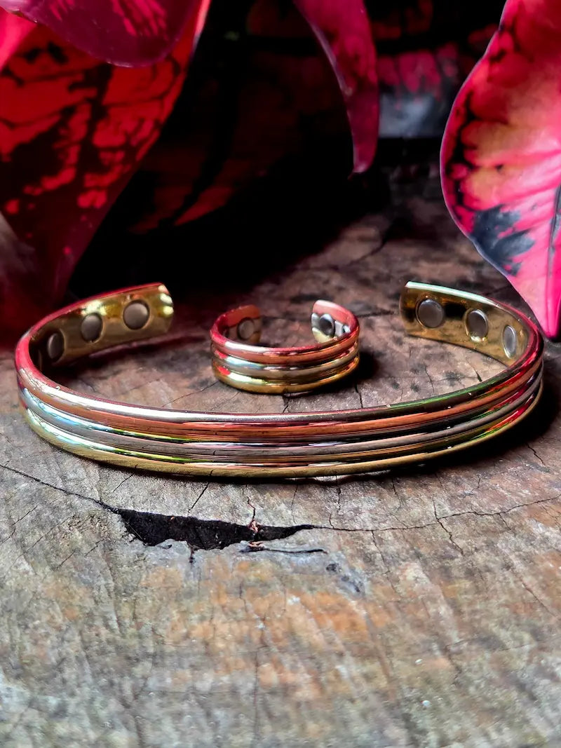 Tricolour copper bracelet and ring on a natural wooden surface eith red leaves in the background