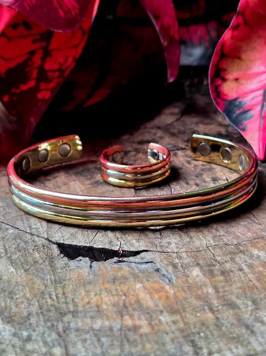 Tricolour copper bracelet and ring on a natural wooden surface eith red leaves in the background