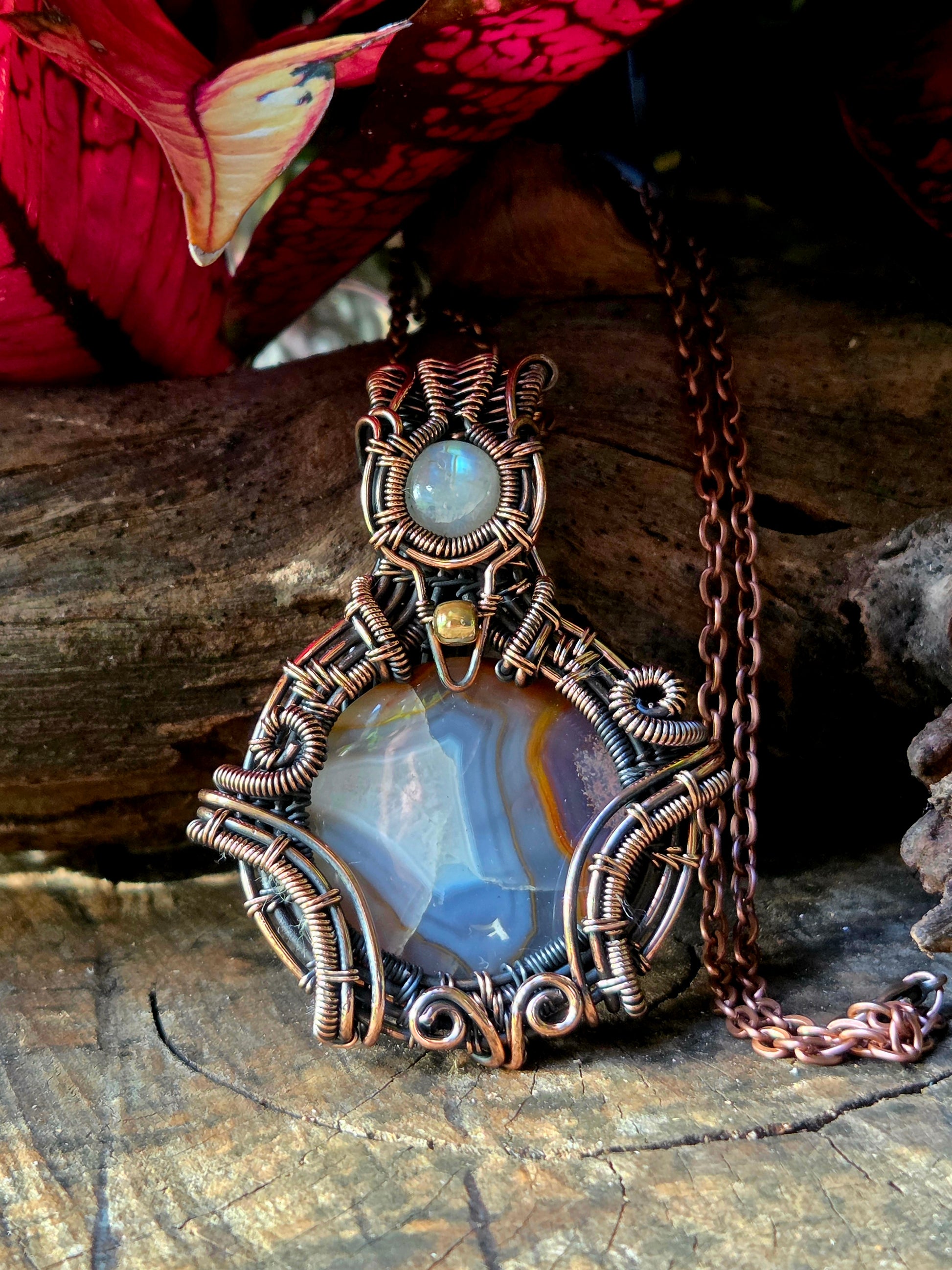 Copper crystal necklace on a natural wooden surface with red leaves in the background 
