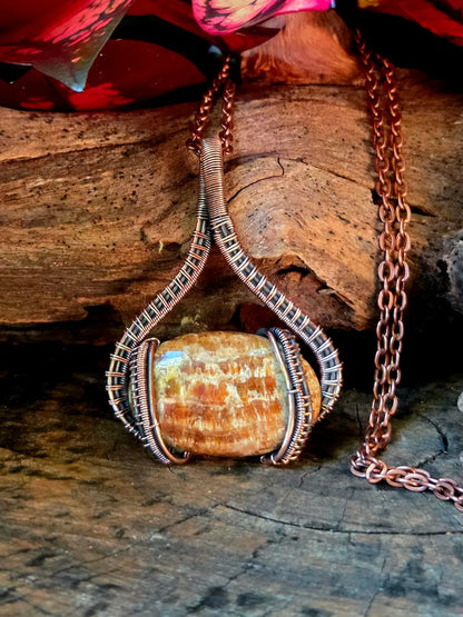 Copper-wrapped stone pendant on a wooden surface