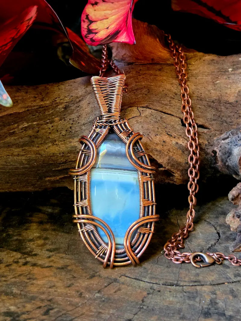 Copper-wrapped pendant with a blue stone on a wooden surface