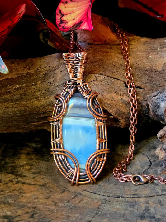 Copper-wrapped pendant with a blue stone on a wooden surface