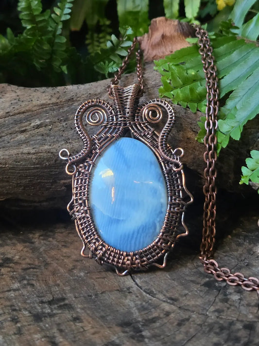 Copper necklace on a natural wooden background with green ferns
