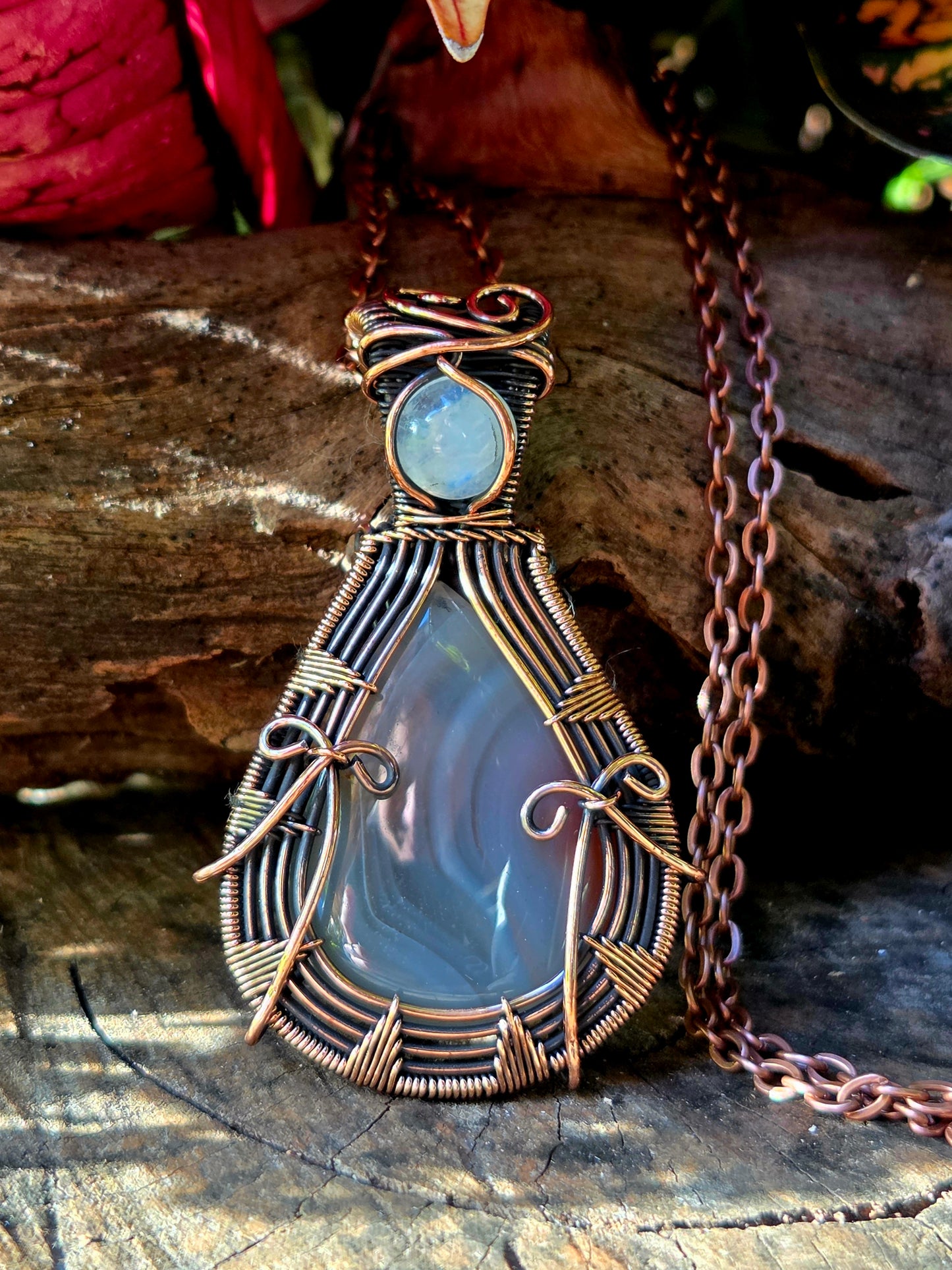 Copper crystal pendant necklace on a natural wooden with red leaves in the background 