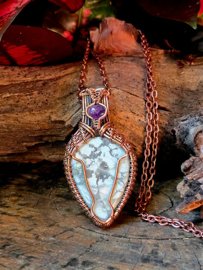 Copper necklace with a howlite pendant placed on a natural wooden surface.