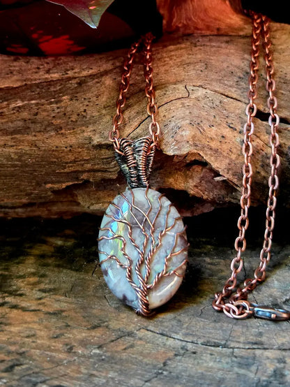 Copper necklace with a tree of life pendant on a wooden surface