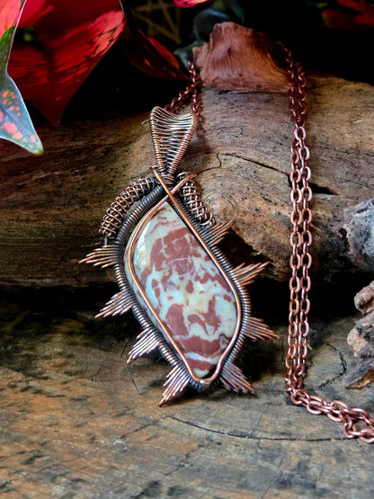 Copper wire-wrapped pendant with a natural stone on a wooden surface