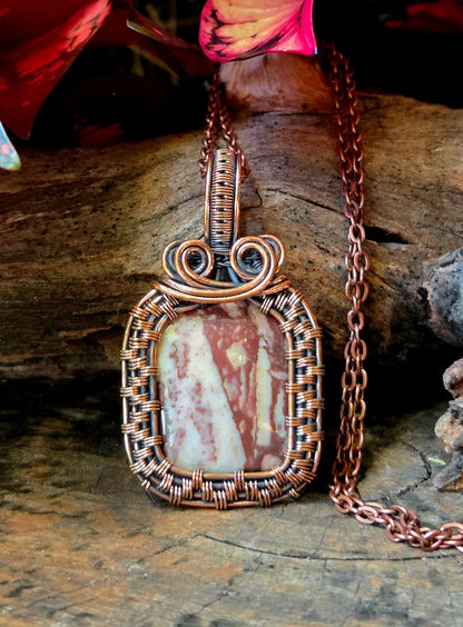 Copper-wrapped pendant with a stone on a wooden surface