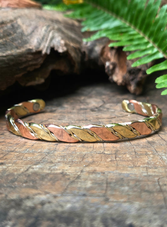 Copper Tricolour bracelet on a wooden surface with ferns in the background