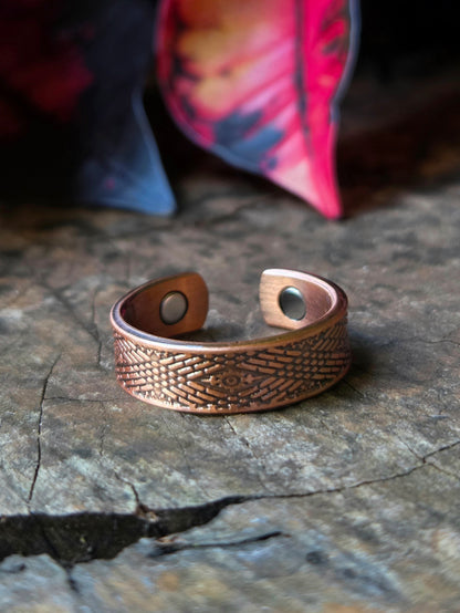 Copper ring on a natural wooden surface with red leaves in the background 