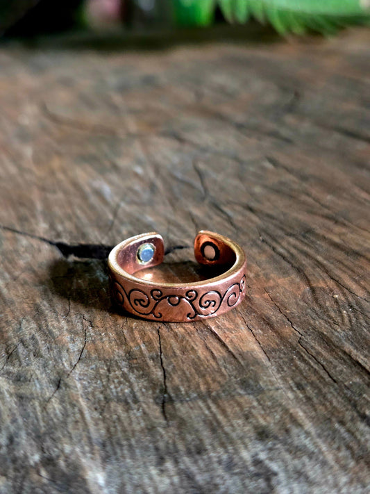 Copper ring with engraved design on a wooden surface