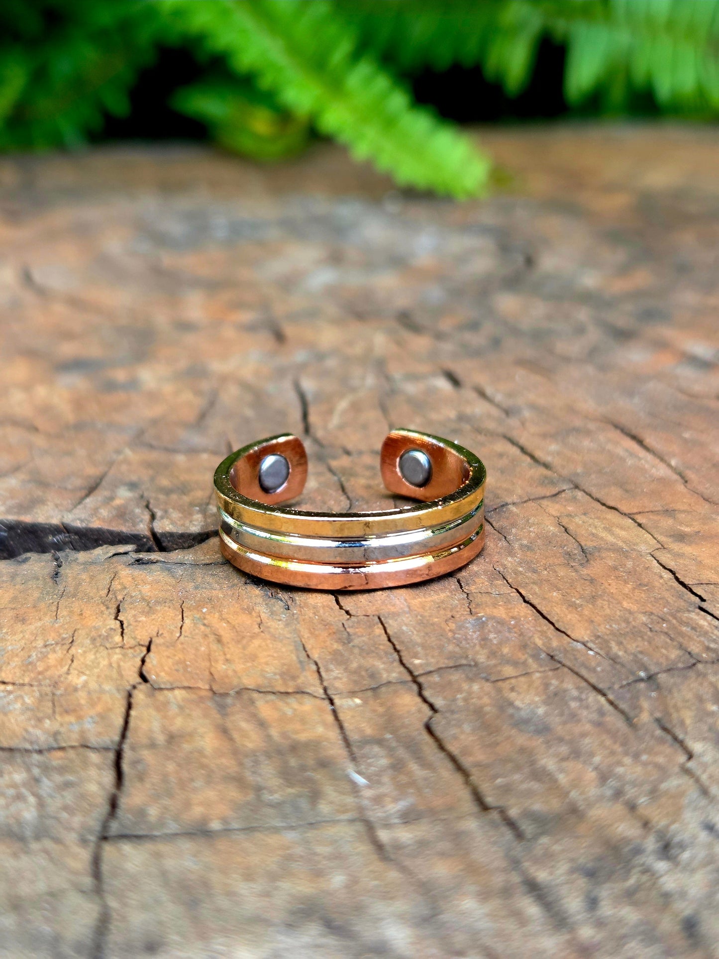 Copper ring on a wooden surface with ferns in the background