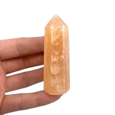 Orange crystal tower held in a hand against a white background