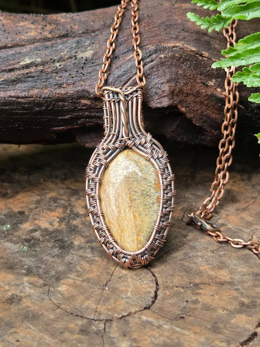 Necklace with a copper pendant on a wooden surface