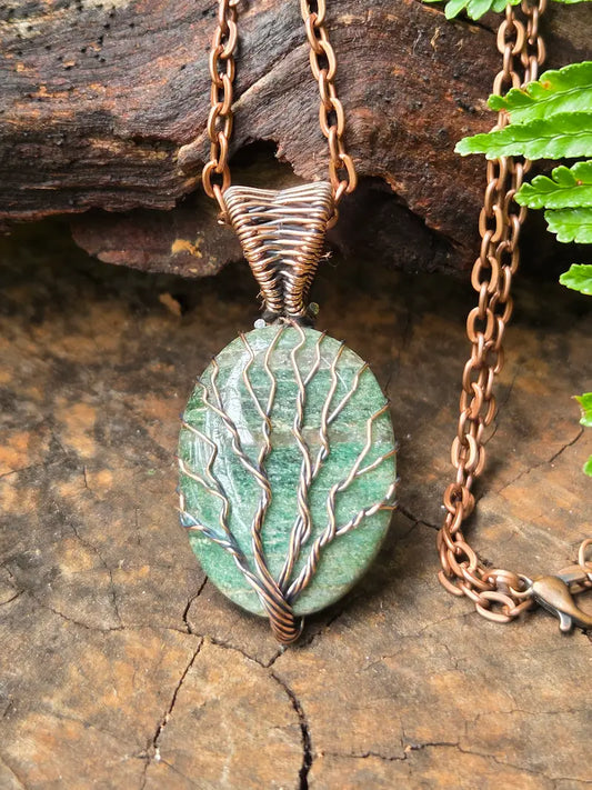 Necklace with a green pendant and copper chain on a wooden surface