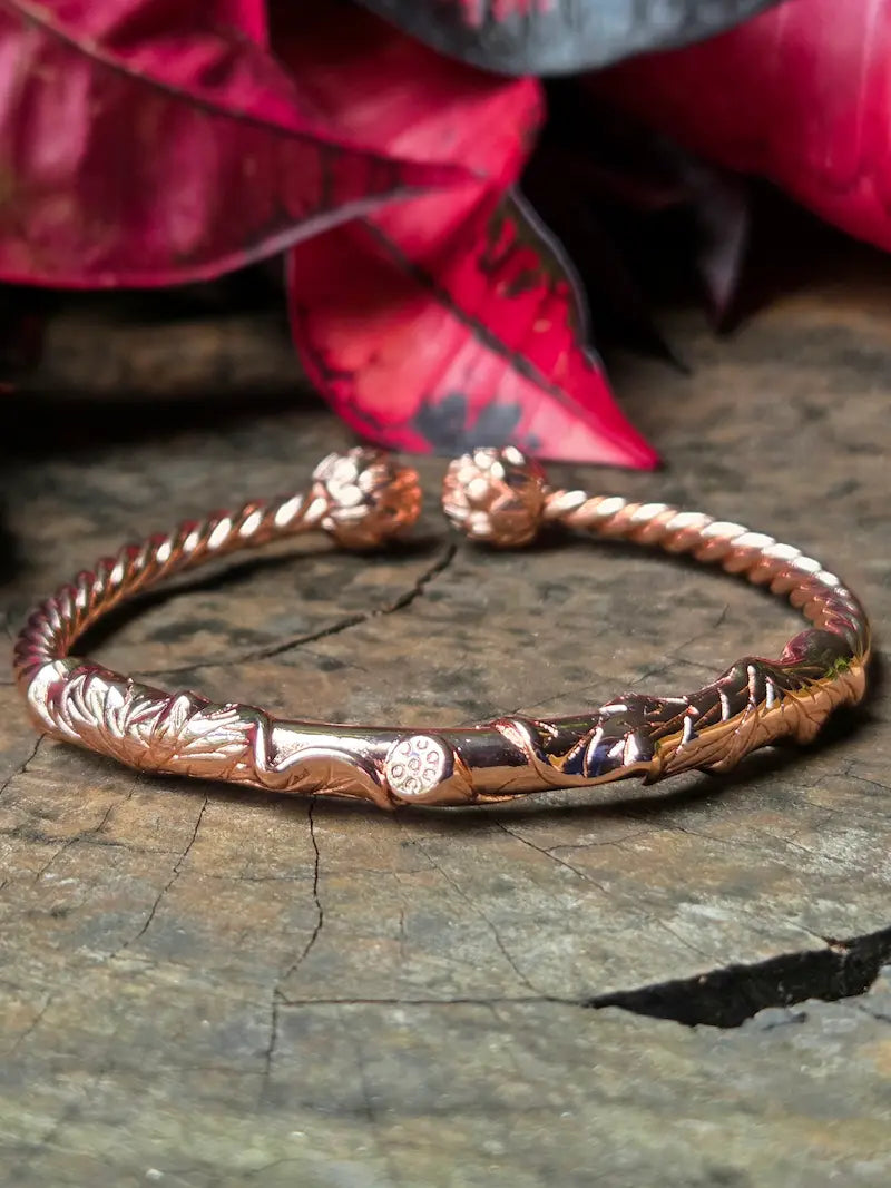 Copper bracelet on a wooden surface with red leaves in the background