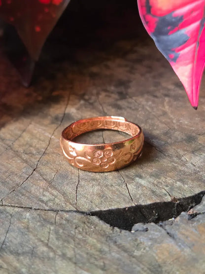 Copper ring on a natural wooden background with red leaves