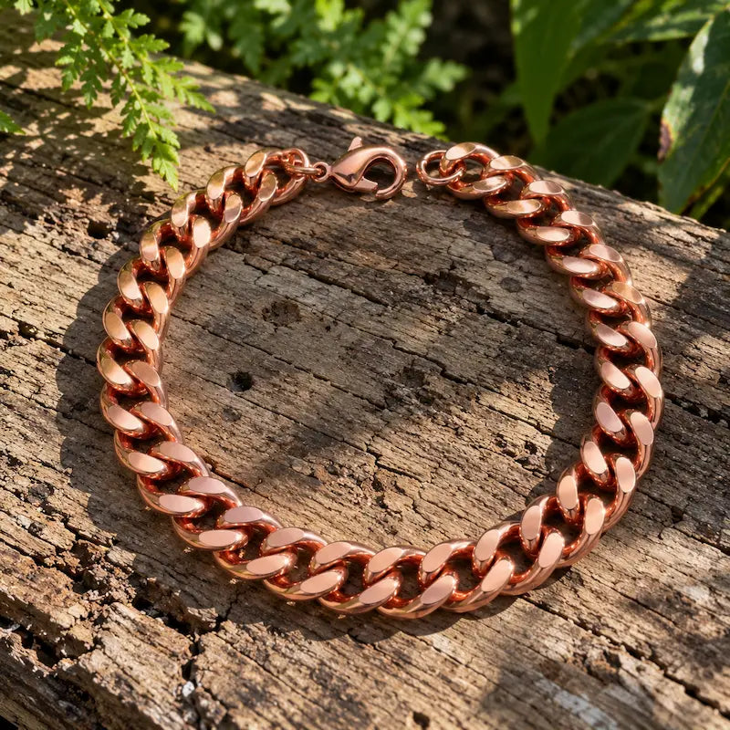 Copper cuban link chain bracelet, resting on a natural wooden surface with green leaves in the background 