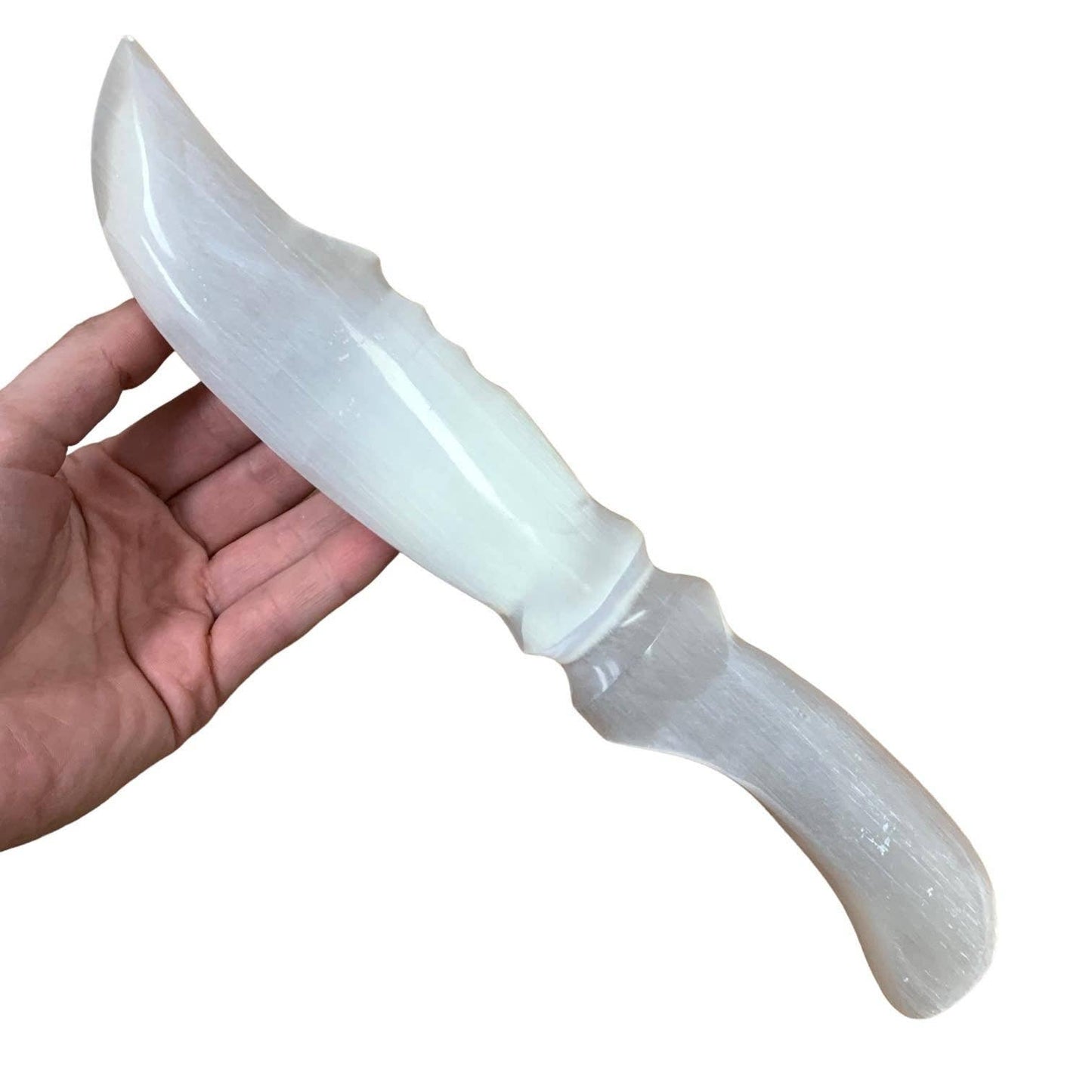 Hand holding a crystal knife with a decorative handle on a white background