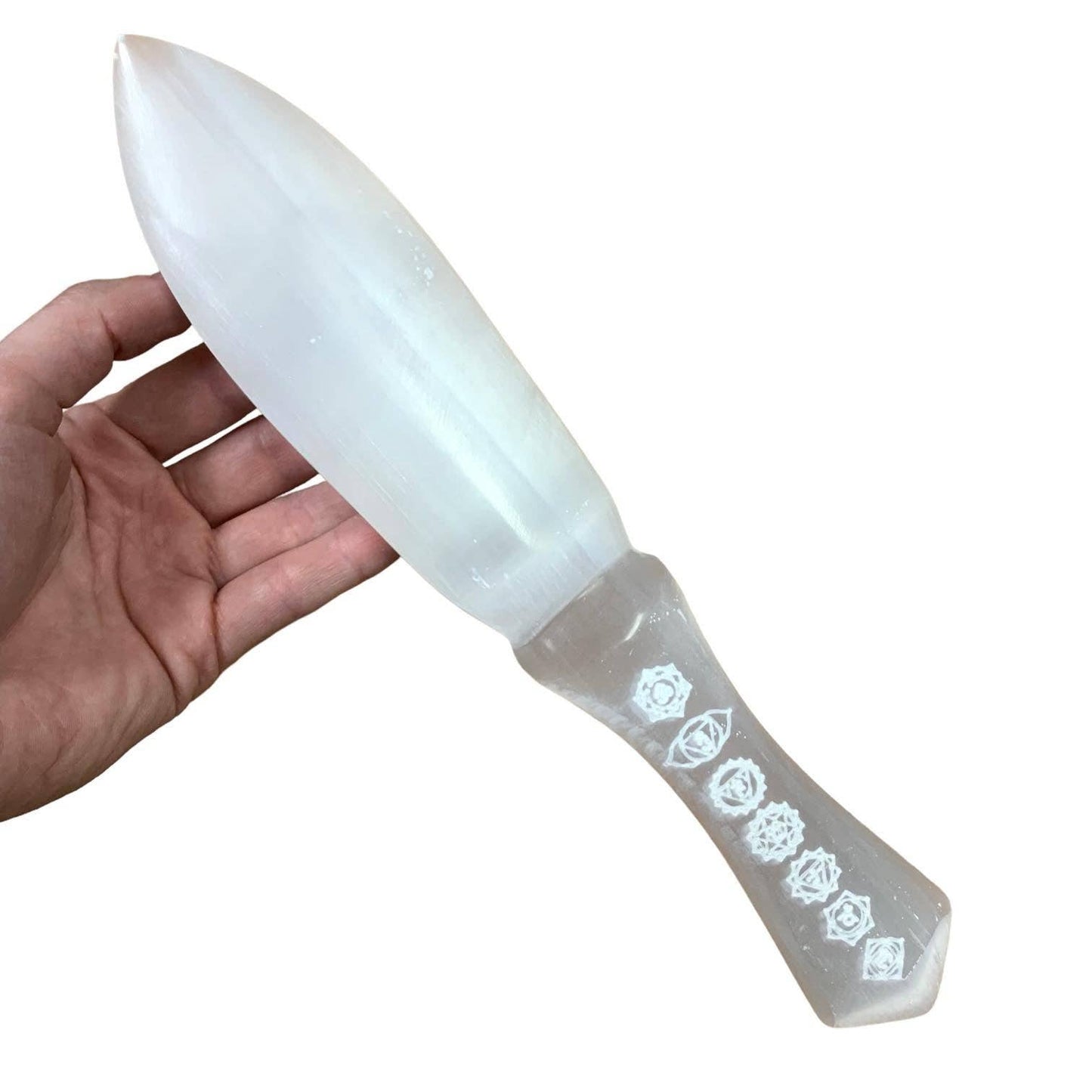 Selenite crystal knife with decorative handle held by a hand on a white background