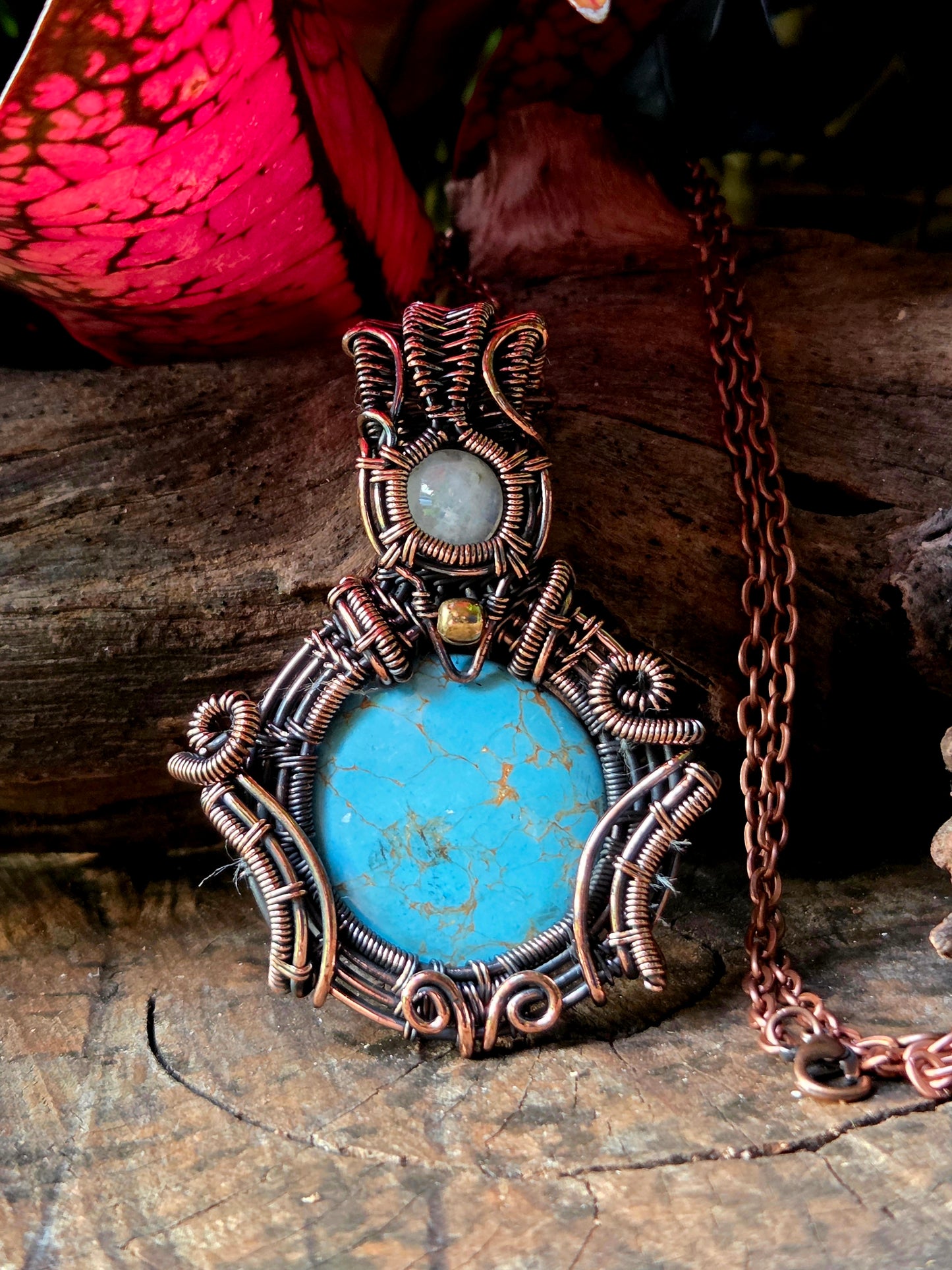 Copper necklace on a natural wooden surface with red leaves in the background 