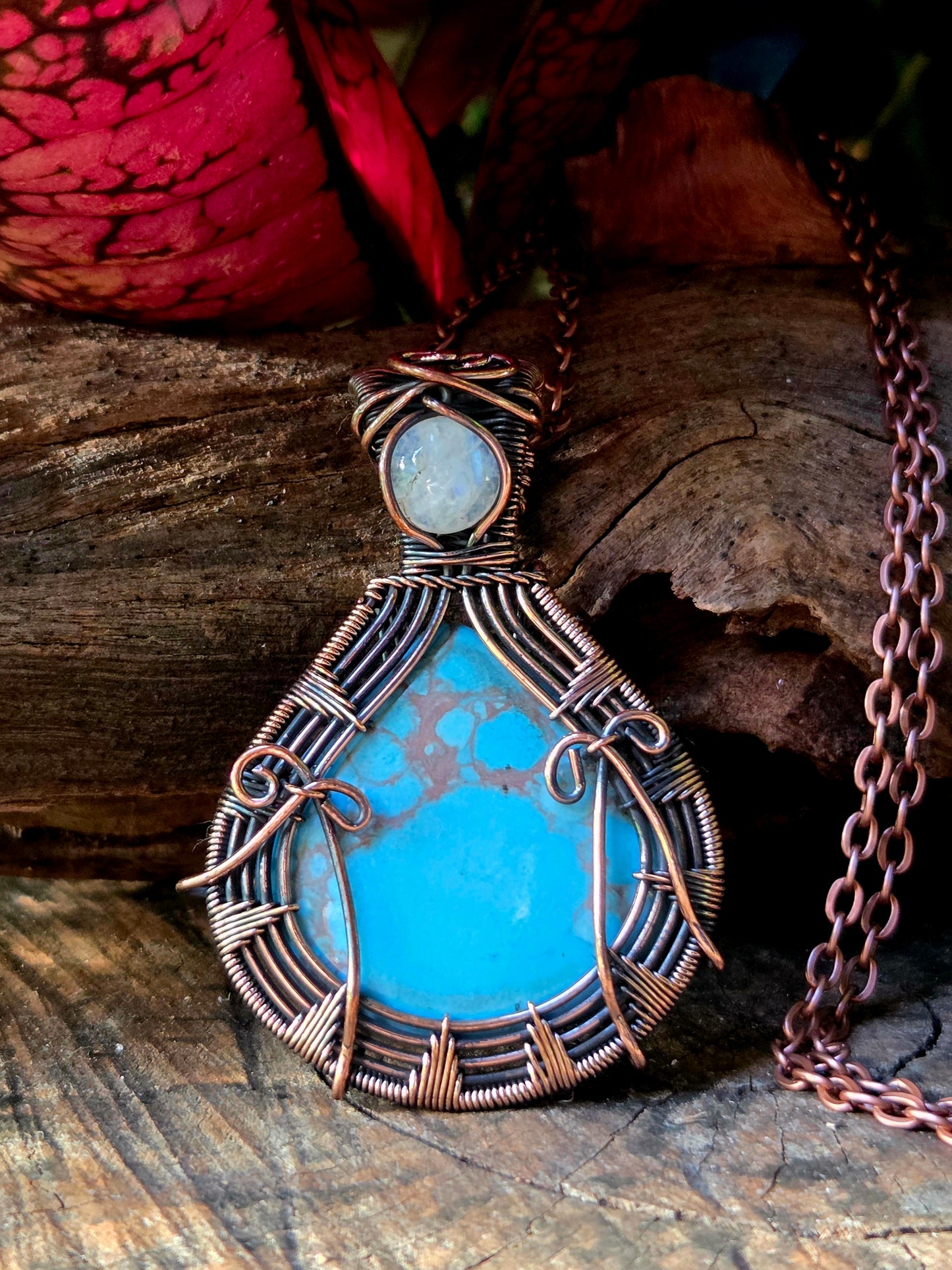 Turquoise copper necklace on a natural wooden surface with red leaves in the background 