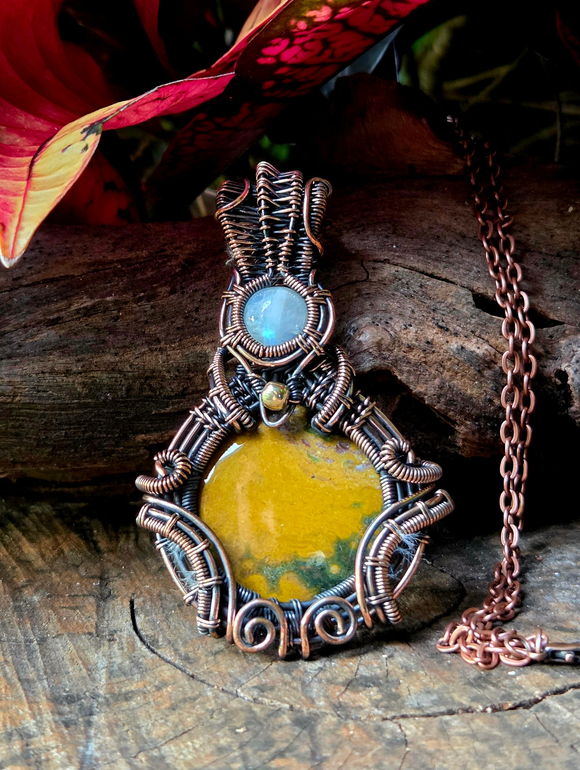 Copper necklace on a natural wooden surface with red leaves in the background 