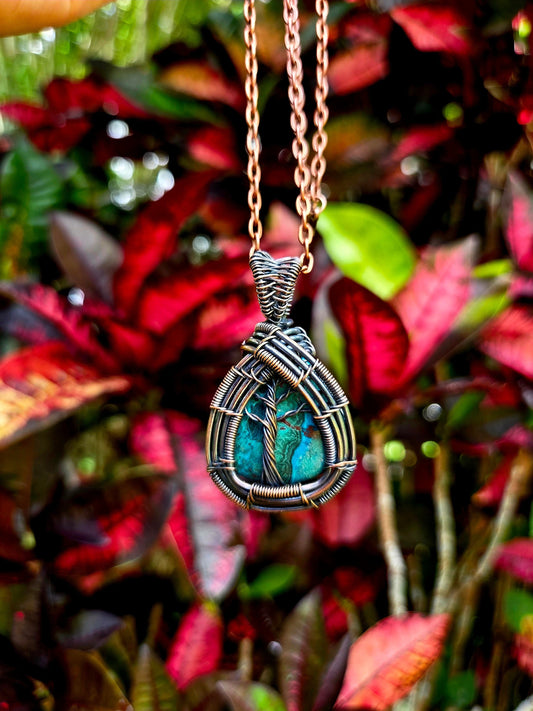 Necklace with a wire-wrapped pendant against a leafy background