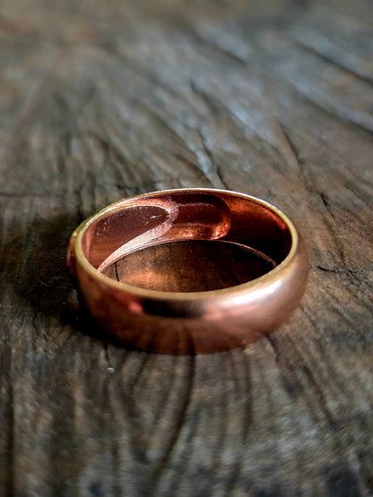 Rose gold ring on a textured wooden surface