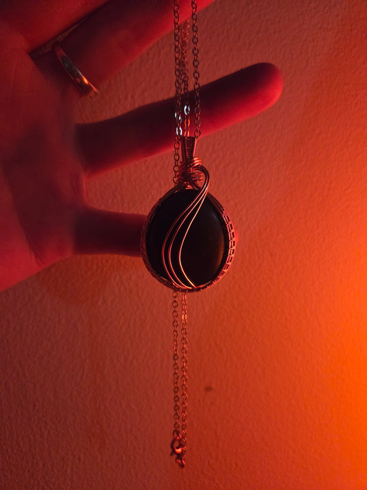 Necklace with a pendant held by a hand against a plain background